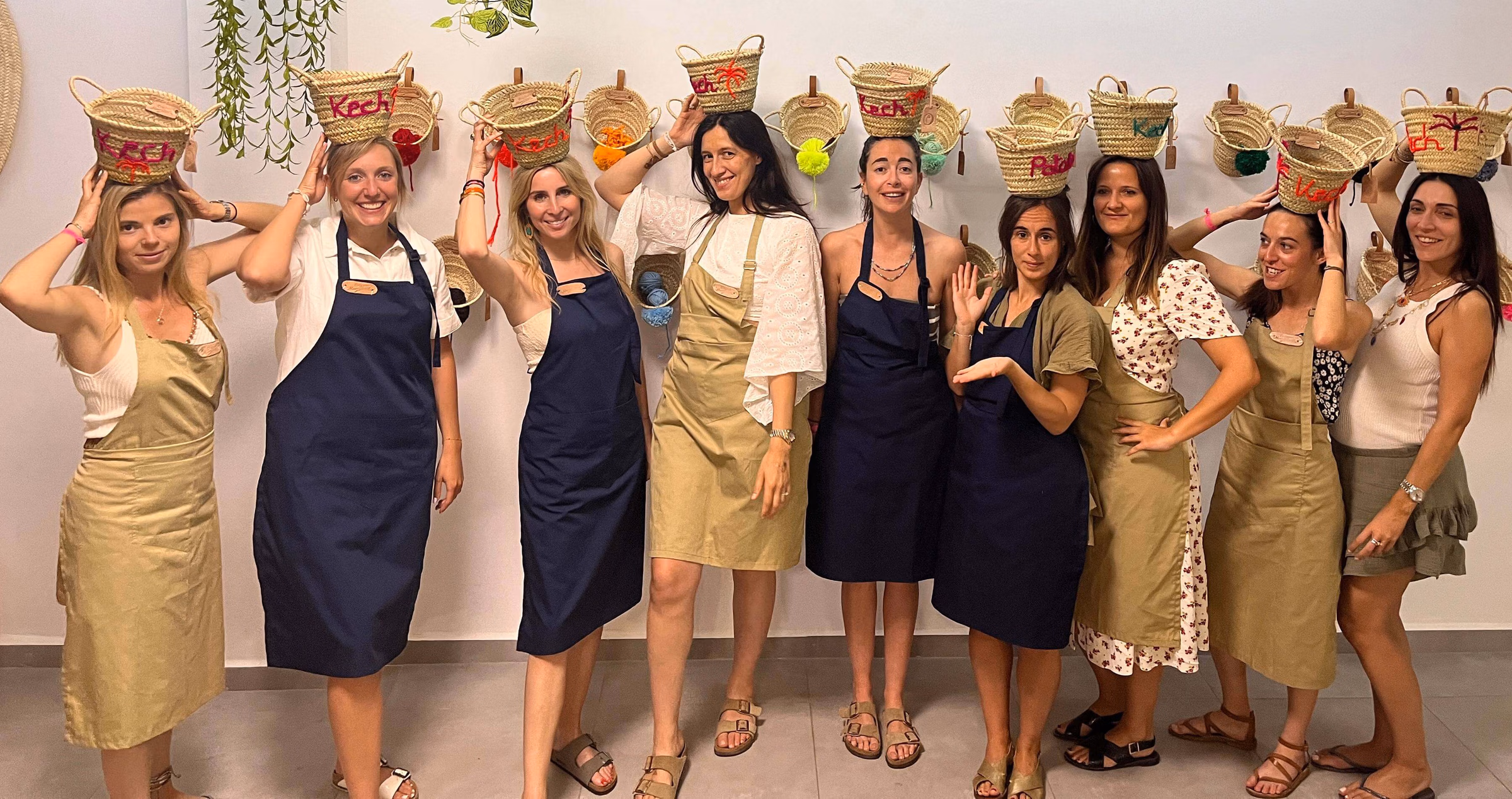 Group of smiling participants holding hand-embroidered baskets and aprons during a creative workshop at Original Marrakech